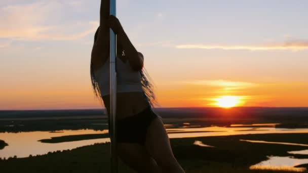 Pole dance au coucher du soleil orange - femme séduisante avec de longues tresses dansant — Video