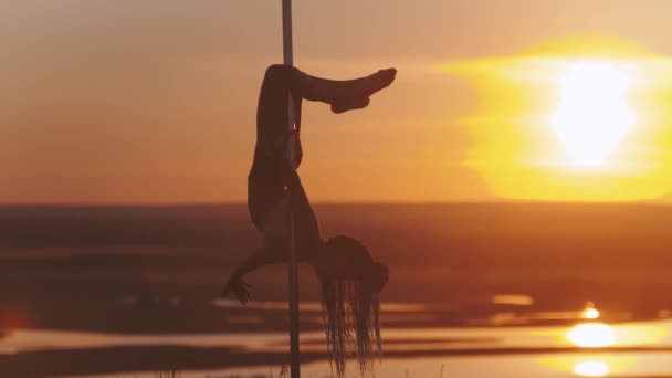 Pole dance au coucher du soleil - jeune femme tenant par le poteau de danse à l'envers — Video