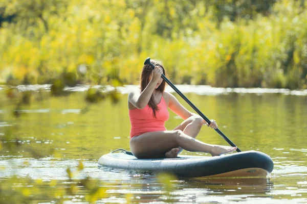 Young woman in pink swimsuit sailing on the inflatable boat with an oar — Stock Photo, Image