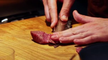 Restoran mutfağı. Şef keskin bıçakla küçük dilimler halinde et kesiyor.