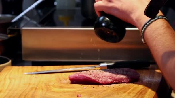 Cocina del restaurante - chef salazón y condimentar el pedazo de carne en el escritorio — Vídeo de stock