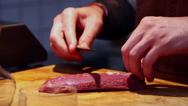Cocina del restaurante - chef cortando carne en rebanadas pequeñas con cuchillo afilado en el escritorio — Vídeos de Stock