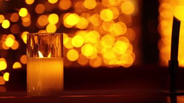 Açık verandadaki restoranların masasında mum yakmak. Arka planda parlak ışıklar.