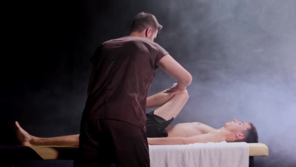 Stüdyoda masaj seansı. Masajcı bacağına bastırıyor ve müşterinin vücuduna bastırıyor. — Stok video