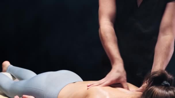 Séance de massage en studio sombre - Massothérapeute souriant massant les femmes de retour avec de l'huile — Video