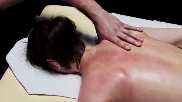 Sessão de massagem no estúdio escuro - terapeuta fazendo uma massagem terapêutica restauradora e adiciona óleo às costas — Vídeo de Stock