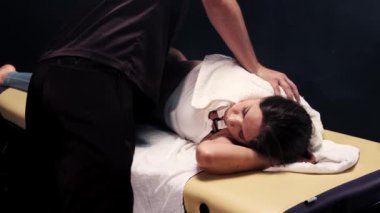 Stüdyoda masaj seansı. Kadın vücudunu havluya bastıran terapist.