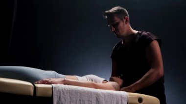 Karanlık stüdyoda masaj seansı. Kadın boynuna masaj yapan terapist.