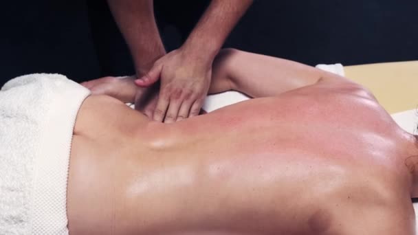 Sesión de masaje en el estudio - terapeuta masajeando el lomo de las mujeres mientras ella está acostada en un sofá — Vídeo de stock
