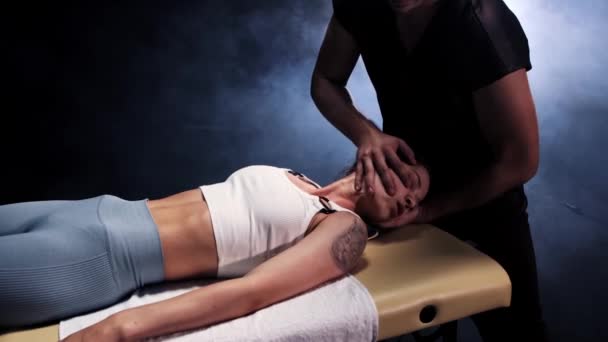 Massage session in the dark studio - therapist turning the womans neck to the sides — Stock Video