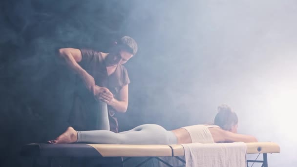 Massage session i svart rökig studio - man terapeut massera unga kvinnor fot — Stockvideo