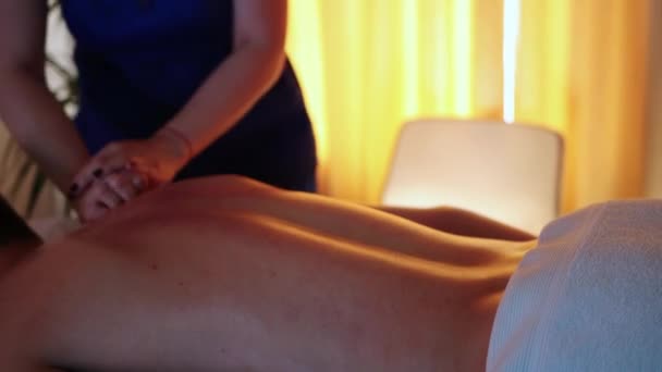 Massage im Wellnesszentrum bei warmem Licht - Ärztin massiert ihre Klienten mit Öl im Rücken und Nacken — Stockvideo