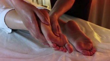 Sıcak ışık altında masaj stüdyosunda. Terapist işini yapıyor. Ayak masajı yapıyor.