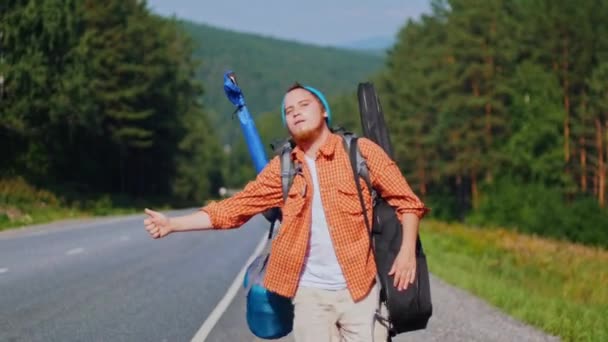 Бородатый мужчина с большим рюкзаком ловит грузовик на дороге — стоковое видео