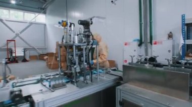 Koruyucu tıbbi maskelerin endüstriyel üretimi. Koruyucu kostüm ve eldiven giyen işçi maskeleri bir araya topluyor.