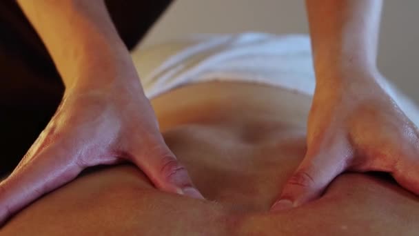 Сеанс масажу в спа-студії - терапевт активно масажує свою жінку клієнт назад за допомогою олії — стокове відео