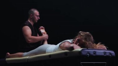 Kanepede uzanmış bir kadın ve ayak masajı yapıyor.