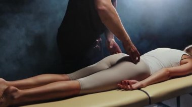 Young woman lies on a couch and a therapist pressing on her butt