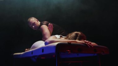 Kanepede yatan bir kadın ve bir kayropraktik uzmanı bacaklarıyla çalışır.
