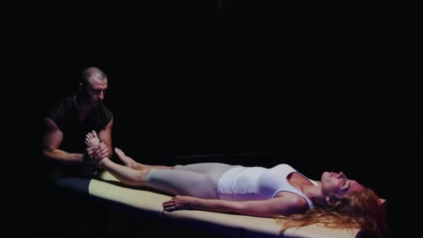 Egy nő fekszik a kanapén, és egy csontkovács a lábával dolgozik. — Stock videók