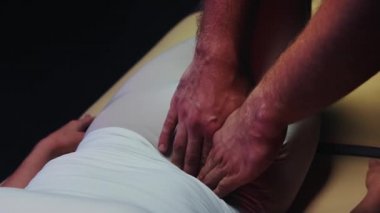 Kanepede uzanmış bir kadın ve bir kayropraktik uzmanı vücuduyla çalışıyor - karnının kenarına baskı yapıyor.