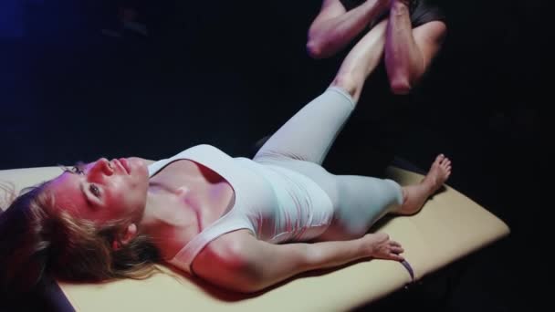 Massage session - kvinna liggande på en soffa och en kiropraktor arbetar med benen — Stockvideo
