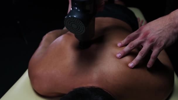 Хиропрактика в студии - терапевт, массирующий спину своего клиента с помощью устройства — стоковое видео