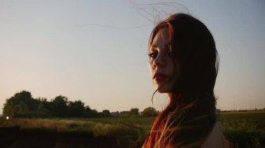 Genç romantik kadın gün batımında nehir kenarında duruyor.