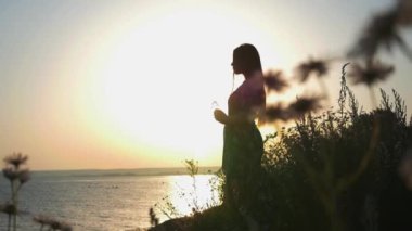 Gün batımında suyun kenarında duran açık elbiseli genç romantik kadın.