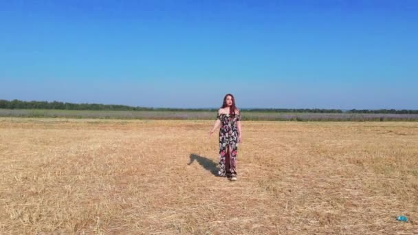 Mujer joven romántica en vestido suelto caminando en el campo amarillo — Vídeo de stock