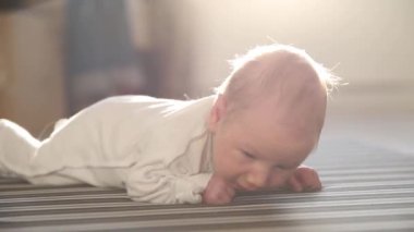 Yeni doğmuş bir bebek yerde yatıyor ve hafifçe hareket ediyor.