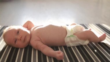 Gün ışığında sırtüstü uzanmış, gülen küçük bir bebek.