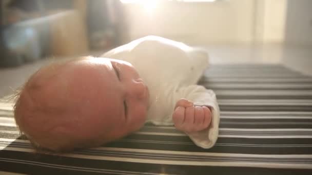 A little newborn baby lying on his back in the bright flat — Stock Video