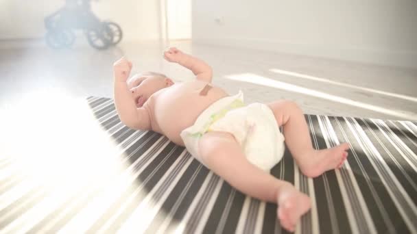 Ένα νεογέννητο μωρό με λευκή πάνα κοιμάται στο κρεβάτι και κινείται στον ύπνο του. — Αρχείο Βίντεο