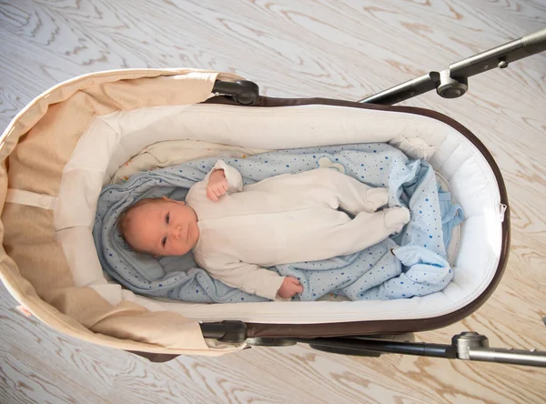En liten söt nyfödd bebis som ligger i barnvagnen — Stockfoto