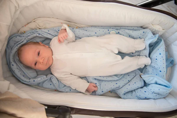 En liten söt nyfödd bebis som ligger i en barnvagn — Stockfoto