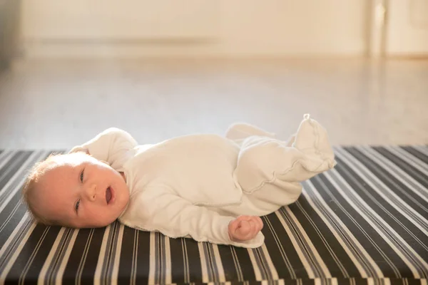 Ett litet gäspande nyfött barn som ligger på rygg — Stockfoto