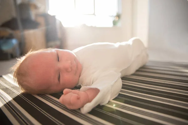 Um bebé recém-nascido de fato branco deitado de costas — Fotografia de Stock