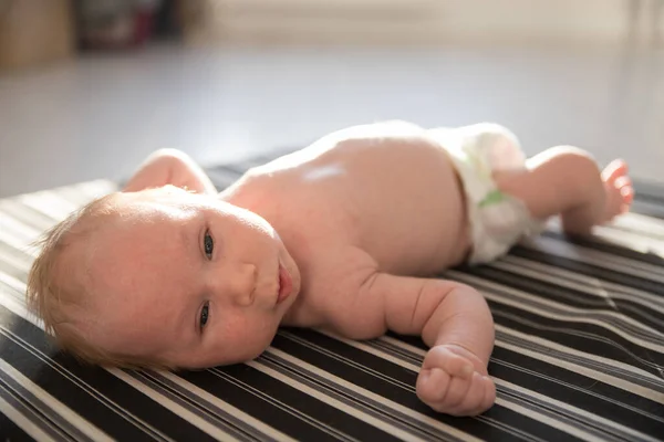 Ett litet nyfött barn i en vit blöja på ryggen. — Stockfoto