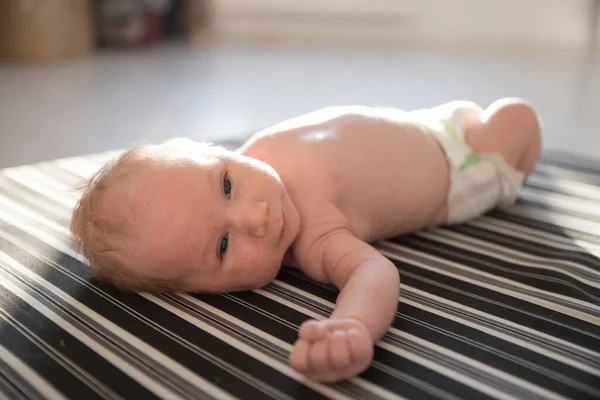 Ein kleines Baby in einer weißen Windel auf dem Rücken liegend — Stockfoto