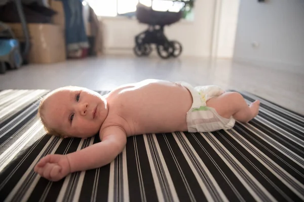 Um bebê recém-nascido em uma fralda deitado de costas — Fotografia de Stock