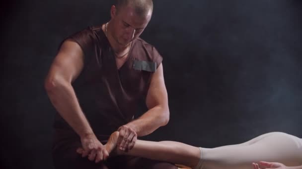 Frau liegt auf einer Couch und ein Chiropraktiker arbeitet mit dem Fuß — Stockvideo