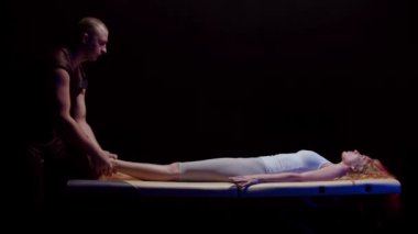 Bir kayropraktik uzmanıyla seans. Sırtüstü uzanmış genç bir kadın. Terapist aniden bacağını çıkarıyor.