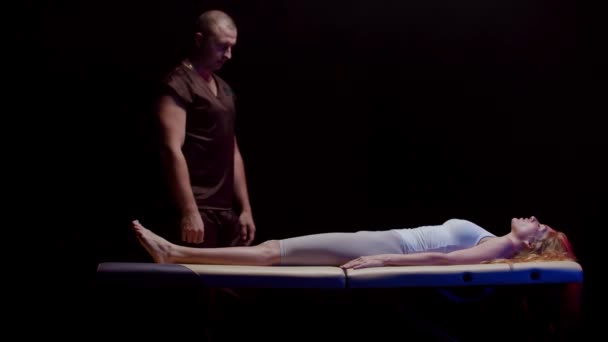 Sitzung mit einem Chiropraktiker - junge Frau liegt auf dem Rücken und der Therapeut beugt ihr Bein zu ihrem Körper — Stockvideo