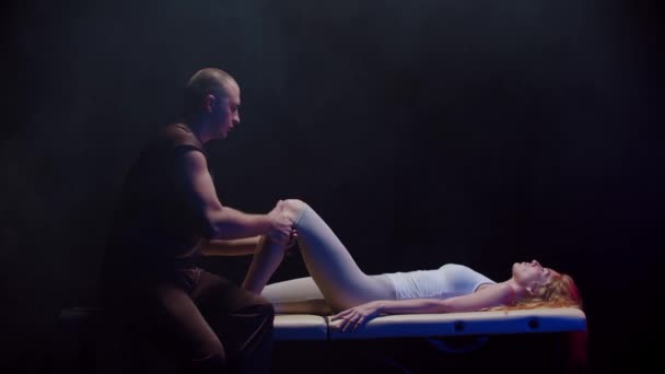 Session egy csontkovács - fiatal nő fekszik a hátán, és a terapeuta dolgozik a lábával — Stock videók