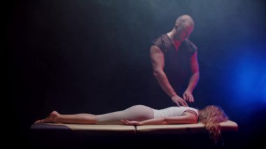 Bir kayropraktik uzmanıyla seans, genç bir kadın yüzüstü yatıyor ve terapist sırtına dokunuyor.