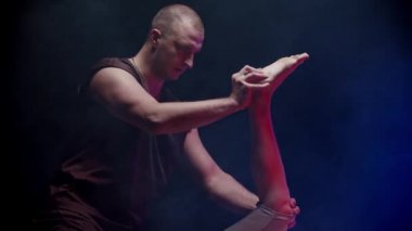 Genç bayan müşteri sırt üstü yatıyor ve terapist bacağını eğip vücuduna doğru hareket ettiriyor.