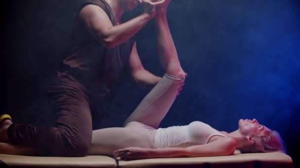 Jovem deitada de costas e a terapeuta dobra a perna e move-a em direção ao corpo — Vídeo de Stock