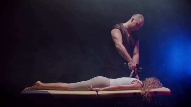 Stüdyoda kayropraktik terapi. Genç bir kadının sırtına bir cihaz kullanarak masaj yapan bir erkek terapist. — Stok video