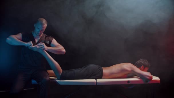 Thérapie chiropratique dans le studio sombre - un thérapeute massant les pieds de ses clients - appuyant sur ses orteils — Video